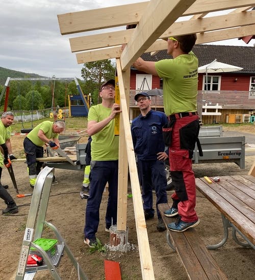 Group of volunteers helping each other to put together wooden construction